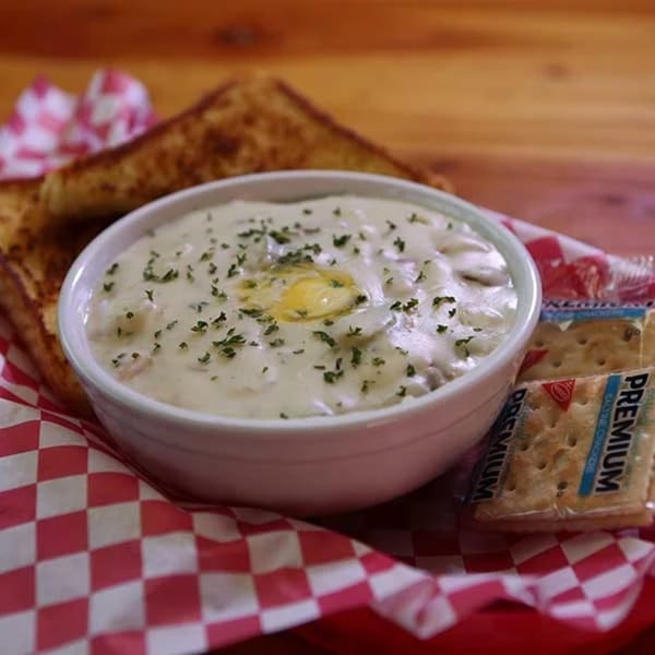 Creamy soup with parsley and butter, served with toasted bread and crackers on a checkered liner.