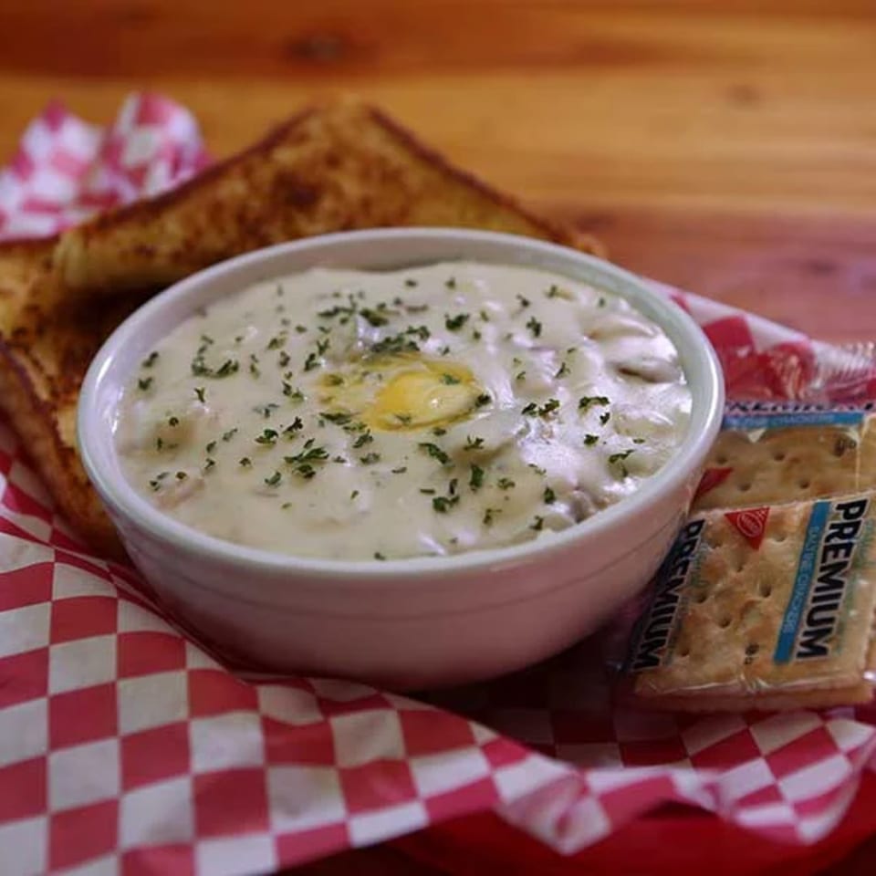 Creamy soup with parsley and butter, served with toasted bread and crackers on a checkered liner.