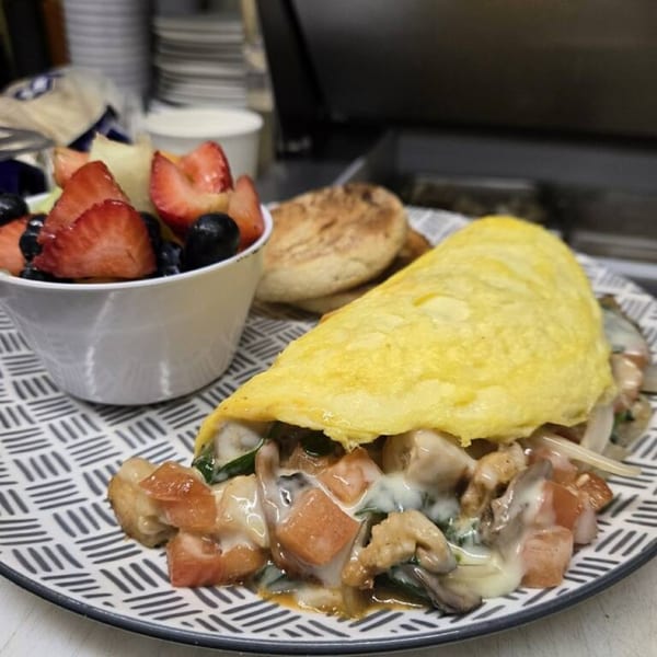 A Gridiron Grill & Tap House omelet with fruit and an English muffin on a patterned plate.