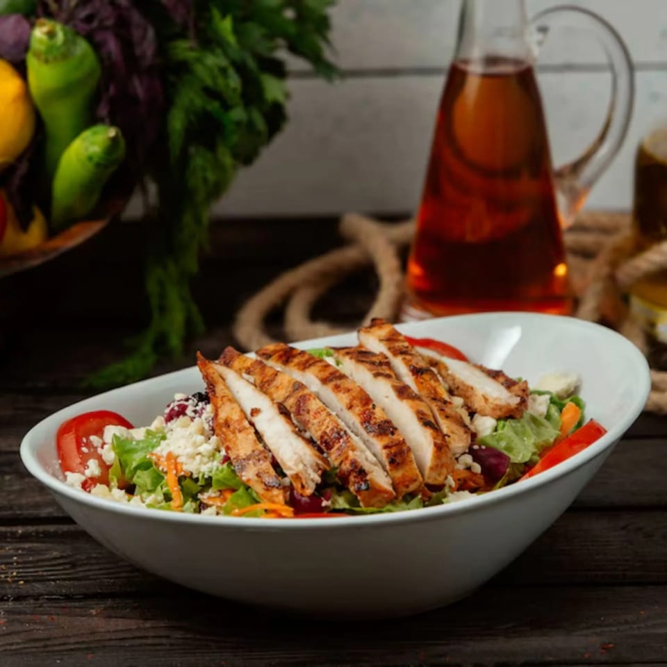 Grilled chicken salad with lettuce, tomatoes, feta, and dressing, from Gridiron Grill & Tap House.