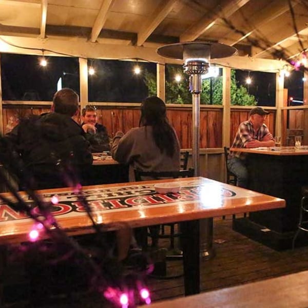 Patrons enjoying the outdoor patio at Gridiron Grill & Tap House, illuminated by string lights and a patio heater.