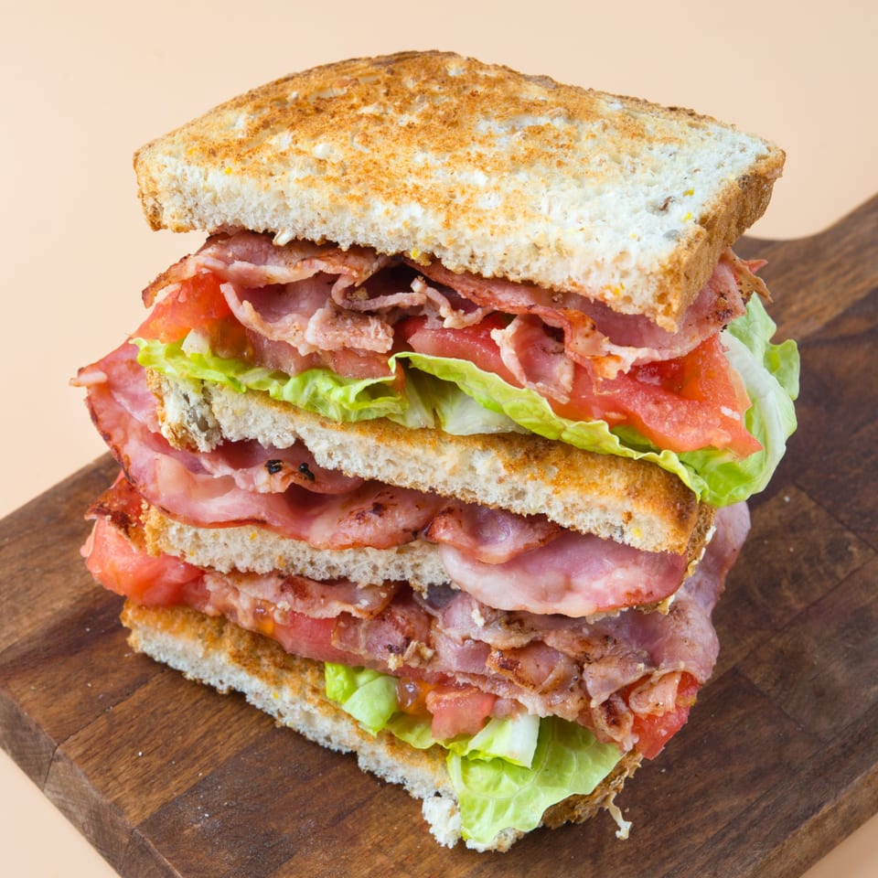 A towering Gridiron Grill & Tap House BLT sandwich with bacon, lettuce, and tomato on toasted bread.