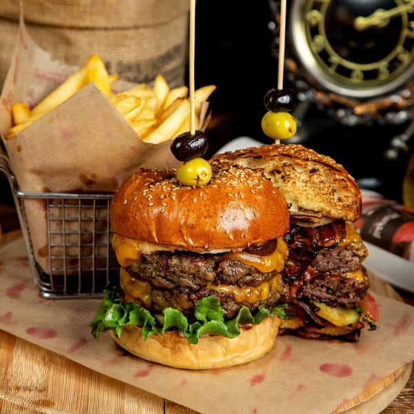 Two Gridiron Grill & Tap House double cheeseburgers with fries in a metal basket.